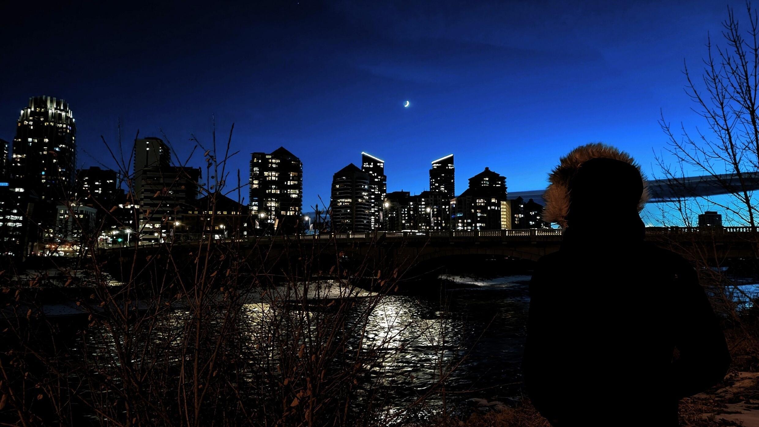 Un passant observe la lune au bord de la rivière Bow, à décembre Calgary, le 16 2023.